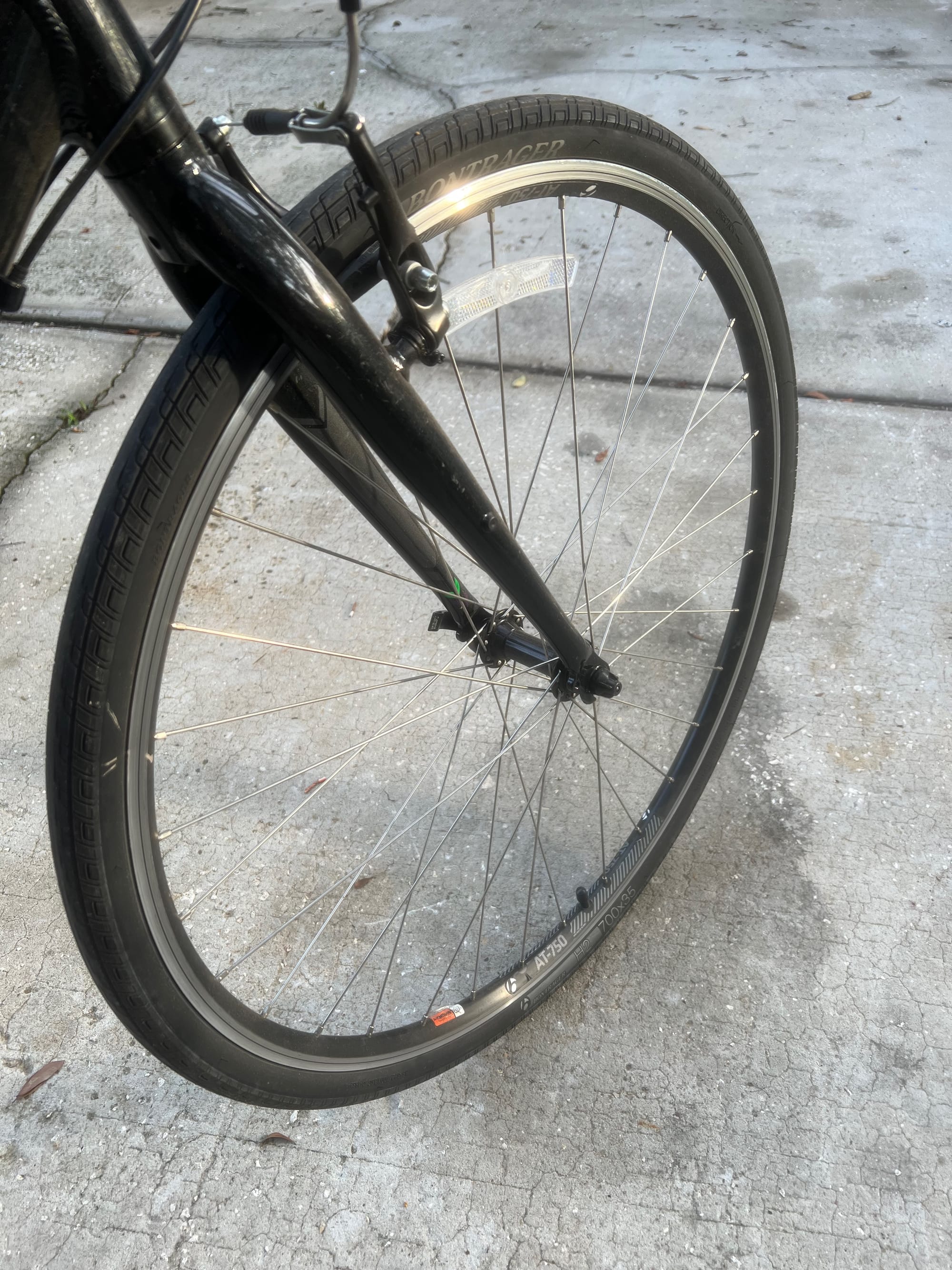 The front wheel of a bicycle with a black spoke coming down to connect the hub.