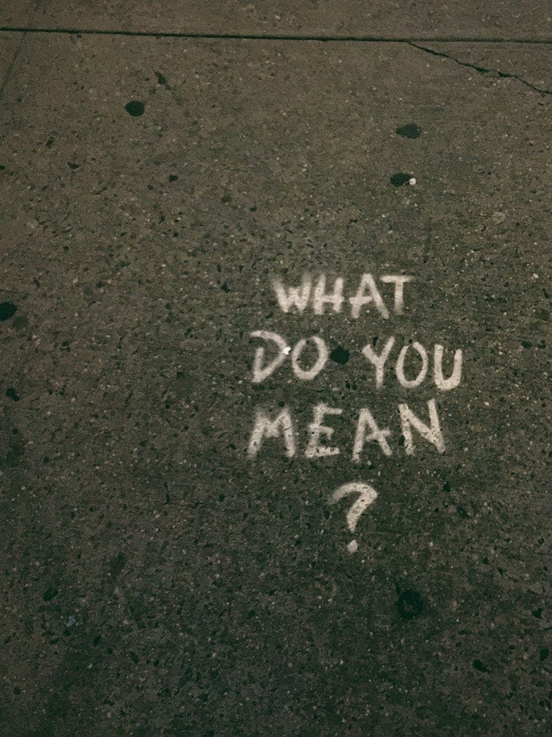 chalk writing on asphalt saying "What do you mean?"